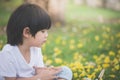 Little Asian boy sitting under the tree and drawing in notebook