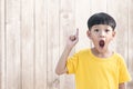 Little asian boy thinking and pointing finger up. Asian Child looking excited and surprised with wooden wall background Royalty Free Stock Photo