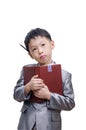 Little Asian boy thinking in suit standing with a diary Royalty Free Stock Photo