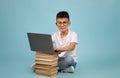 Little Asian Boy Wearing Eyeglasses Sitting With Laptop And Stack Of Books Royalty Free Stock Photo