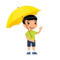 Little asian boy with yellow umbrella smiles and waves his hand.