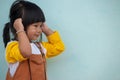 Little asian child, Girls wearing brown bibs Raise your hands, close your ears, don`t want to hear. Royalty Free Stock Photo