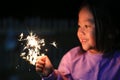 Little Asian child girl enjoy playing firecrackers. Focus at fire sparklers