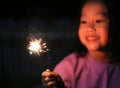 Little Asian child girl enjoy playing firecrackers. Focus at fire sparklers Royalty Free Stock Photo