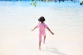 Little Asian child girl enjoys and running into big Swimming pool outdoor on holidays. Rear view children having fun Royalty Free Stock Photo