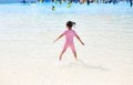 Little Asian child girl enjoys and running into big Swimming pool outdoor on holidays. Rear view children having fun Royalty Free Stock Photo