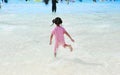 Little Asian child girl enjoys and running into big Swimming pool outdoor on holidays. Rear view children having fun Royalty Free Stock Photo