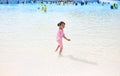 Little Asian child girl having fun and running into aqua park on holidays. Back view kid enjoys in big swimming pool outdoor Royalty Free Stock Photo