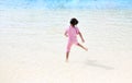 Little Asian child girl having fun and running into aqua park on holidays. Back view kid enjoys in big swimming pool outdoor Royalty Free Stock Photo