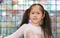 Little Asian child girl lean against a net playing and hanging in indoors playground. Active girl having fun at sport center on