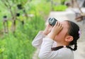 Little Asian child girl looking up in sky through the binoculars in the nature field outdoor. Explore and adventure concept Royalty Free Stock Photo