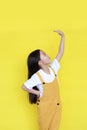Little asian child girl measures the growth on yellow background. Kid estimate her height by hand Royalty Free Stock Photo