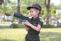 Little Asian child girl in pilot soldier suit costume with holding gun in hands at the garden