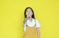 Little asian child girl showing finger number one isolated on yellow background. Kid counting with fingers for education concept.