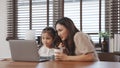 Little asian daughter online education using laptop computer with mother feeding noodles Royalty Free Stock Photo