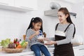 Little asian girl child is eating food and milk yogurt with mother in kitchen at home on holiday. Family warmth and baby`s growth Royalty Free Stock Photo