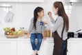 Little asian girl child is eating food and milk yogurt with mother in kitchen at home on holiday. Family warmth and baby`s growth Royalty Free Stock Photo