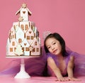 Little asian girl in crown and purple dress with ginger cookie cake for birthday party celebration