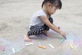 Little asian girl drawing with chalk on the sidewalk Royalty Free Stock Photo