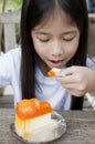 Little Asian girl enjoy orange cheese pie.