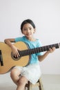 Little Asian girl learning how to play acoustic classic guitar for jazz and easy listening song select focus shallow depth of
