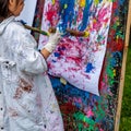 Little Asian girl painting on board with stick outdoors in park. Happy childhood and creativity Royalty Free Stock Photo