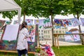 Little Asian girl painting on board with stick outdoors in park. Happy childhood and creativity Royalty Free Stock Photo