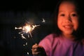 Little Asian girl playing fire sparklers in the dark