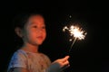 Little Asian girl playing fire sparklers in the dark.