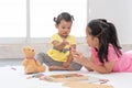 Little Asian girl playing with her younger sister, drawing together. Infant girl learns drawing with sister