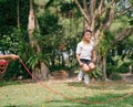 Little Asian girl playing with skipping rope jumping at green nature park.