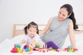 Little girl playing toys with her mother on bed at home Royalty Free Stock Photo