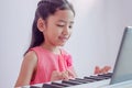 A little Asian girl playing the white keyboard with happiness