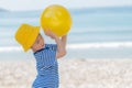 Little asian girl playing yellow ball on the beach in summer. Little girl have enjoy and happy. Royalty Free Stock Photo