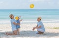 Little asian girl playing yellow ball with mom and dad on the beach in summer.