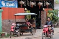 Little Asian girl plays in a motor rickshaw, a scooter rides along the road