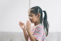 Little asian girl praying on white sofa in living room at home Royalty Free Stock Photo