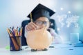 Little Asian girl putting the coin into piggy bank and smile with happiness for money saving to wealthness in the future of Royalty Free Stock Photo