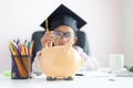 Little Asian girl putting the coin into piggy bank and smile with happiness for money saving to wealthness in the future of Royalty Free Stock Photo