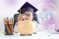 Little Asian girl putting the coin into piggy bank and smile with happiness for money saving to wealthness in the future of Royalty Free Stock Photo