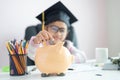 Little Asian girl putting the coin into piggy bank and smile with happiness for money saving to wealthness in the future of Royalty Free Stock Photo