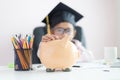 Little Asian girl putting the coin into piggy bank and smile with happiness for money saving to wealthness in the future of Royalty Free Stock Photo