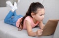 Little Asian Girl Reading Book Lying On Couch At Home Royalty Free Stock Photo