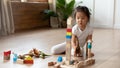 Little asian girl seated on warm floor plays wooden blocks Royalty Free Stock Photo