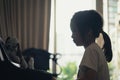 Little girl silhouette playing piano at home