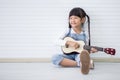 little asian girl sitting playing ukulele on white background with copy space Royalty Free Stock Photo