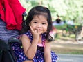 Little asian girl sitting in a stroller at public park. She have be smile and love in sign language. Royalty Free Stock Photo