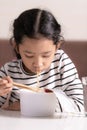 Little Asian girl sitting at white table to eating instant noodle Royalty Free Stock Photo