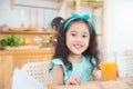 Little girl smiling while drinking orange juice at breakfast table in the morning Royalty Free Stock Photo