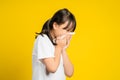 Little asian girl sneeze with napkin paper isolated on yellow background Royalty Free Stock Photo